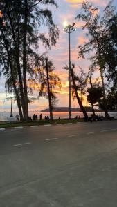 an empty street with trees and a sunset in the background at Global Beach Hostel - Ao Nang in Ban Khlong Haeng +11 photos