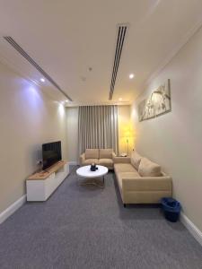 リヤドにあるAsfar Plaza Hotel & Apartmentsのソファとテレビのあるリビングルーム