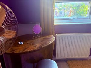 Habitación con mesa, ventilador y ventana. en Tottenham Stay-Diem, en Londres