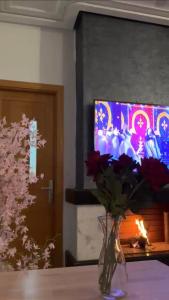 un jarrón de flores sentado en una mesa con un televisor en Fleury, en Fez