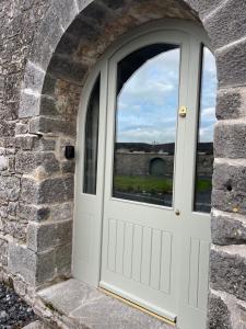 a white door in a stone wall with a window at Crossdrum Courtyard Accommodation in Oldcastle +3 photos
