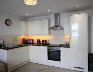 a kitchen with white cabinets and a stove top oven at Luxury 2-Bed Flat Central Ipswich Parking in Ipswich