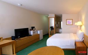 a hotel room with a bed and a flat screen tv at SkyView Swift Current in Swift Current