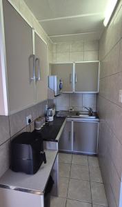 a small kitchen with a sink and a microwave at To C Garden Cottage in Mossel Bay +13 photos