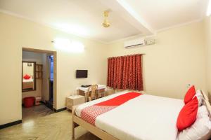 a bedroom with a bed with red pillows at Hotel O Kingston Residency in Vānivilāsa Puram
