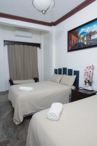 フローレスにあるHostal Casa de Grethelのベッドが2つと壁にテレビがある寝室