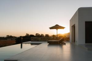 un patio avec un parasol et une chaise et une piscine dans l'établissement Ios Bliss, à Mylopotas