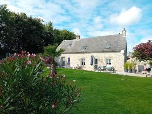 une grande maison en pierre avec une cour herbeuse dans l'établissement Gite La Bignone, à Saint-Marcouf