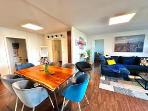 a living room with a wooden table and blue chairs at Modern Lakeview Apartment in Romanshorn