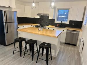 a kitchen with a counter with stools and a refrigerator at Rives de Ste-Anne in Sainte-Anne-de-Beaupré