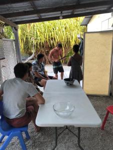 eine Gruppe von Menschen, die um einen weißen Tisch sitzen in der Unterkunft Fare Pū Tea in Rotoava