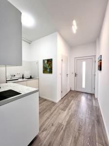 an empty kitchen with white cabinets and wood floors at Wohnung am Rosengarten in Kehl am Rhein