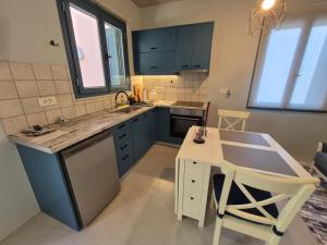 a kitchen with blue cabinets and a table and a table and chairs at Studio Bella in Ancient Epidauros