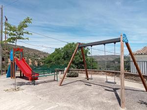 two swings in a playground with mountains in the background at El Almendro De La Tia Teresa in Prados de Armijo