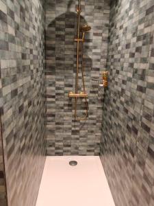 a bathroom with a shower with a tile wall at Gîte du Volcan des Causses in Saint-Jean-dʼAlcapiès