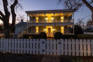 a white fence in front of a house at Victorian Escape-Pool & Hot Tub! in Fredericksburg
