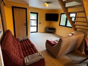 Una sala de estar con un sofá y un televisor. en Gites Douillets Chalet du Vicomte, en Houyet 5 fotos más