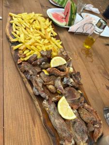 a tray of meat and french fries on a wooden table at Bujtina Liqeni i Shkopetit in Madhesh