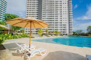 an umbrella and chairs next to a pool with a building at Elemnt Rentals in Santa Marta