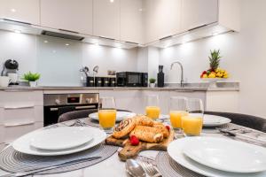 a table with plates of food and glasses of orange juice at Stylish 2BR 2BA Flat in Gravesend Sleeps 4 in Gravesend