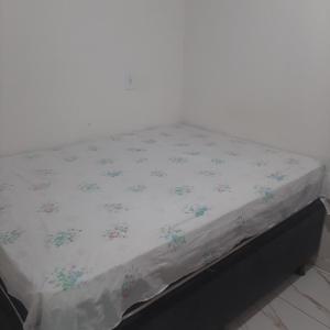 - un lit avec une feuille blanche ornée de fleurs dans l'établissement Quartos na Band, à Telêmaco Borba