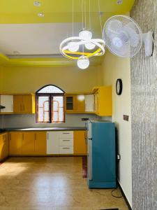 uma cozinha com armários amarelos e um frigorífico azul em Palm Villas Jaffna em Jaffna