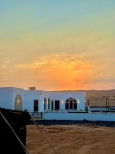 a white building on the beach at sunset at Sunset77 in Al Wāşil