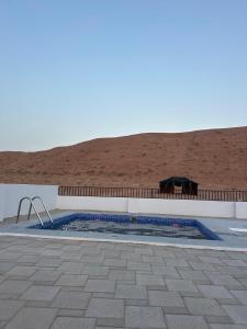 a small swimming pool with a patio and a building at Sunset77 in Al Wāşil +17 photos