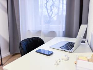 einen Schreibtisch mit einem Laptop und einem Handy in der Unterkunft Modernes Studio mit Balkon & Parkplatz, Wifi- K#1 in Osterholz-Scharmbeck
