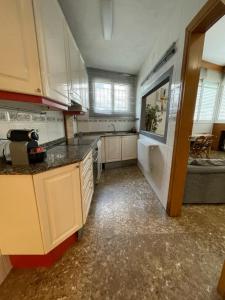 cocina grande con armarios blancos y fregadero en Casa la Luna, en Badalona