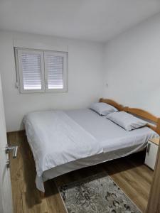 a bed in a white room with two windows at Azar in Bar