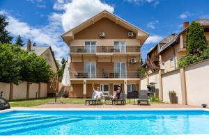 two people sitting at a table in front of a house at Karos Bianco Apartmanház in Zalakaros