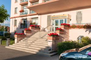 un edificio con escaleras y flores en macetas de flores en Grand Hôtel Filippo Strasbourg Nord, en Niederbronn-les-Bains