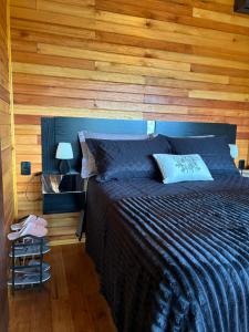 a bedroom with a bed with a wooden wall at Cabanas nascer do sol - Encantada in Barracão