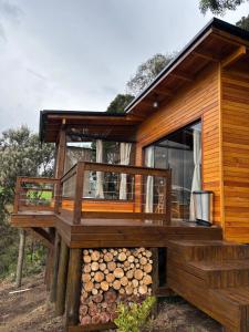 a wooden cabin with a deck and a bunch of logs at Cabanas nascer do sol - Encantada in Barracão