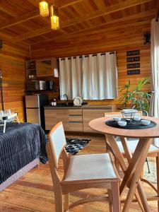 a dining room with a table and a kitchen at Cabanas nascer do sol - Encantada in Alfredo Wagner