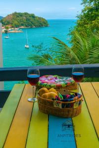 a picnic table with a basket of bread and two glasses of wine at Anfitriões Angra- Flat com Vista Espetacular na Praia Grande in Angra dos Reis