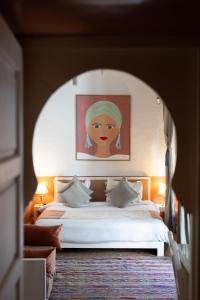 a bedroom with a bed with a painting of a woman at Riad Ajmal in Marrakech +34 photos
