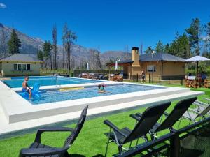 - une piscine avec des chaises et des personnes y jouant dans l'établissement Complejo Turistico Paralelo 42, à Lago Puelo