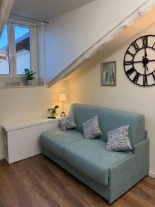 a living room with a blue couch and a clock at Little House Amedeo in Turin