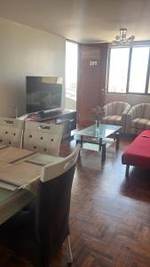 a living room with a television and a table and chairs at Pimentel frente al muelle con balcón in Pimentel