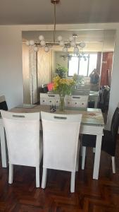 a dining room table with white chairs and a mirror at Pimentel frente al muelle con balcón in Pimentel