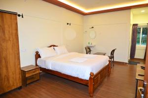 ThandikudiHasvika Hilltop Resort and Hotel的一间卧室，配有一张床、一张桌子和一个水槽