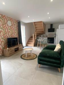 a living room with a green couch and a tv at La chambre aux hommes in Lusignan