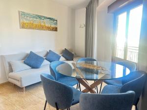a living room with a glass table and blue chairs at Sol 3-Bedroom Apartments in Calpe