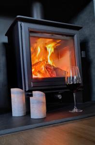 a glass of red wine next to a fireplace at The Barn at Whistley Fields in Devizes