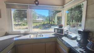 a kitchen with a sink and a microwave and a window at Morada entre Valles in San Carlos de Bariloche
