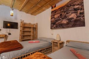 a room with two beds and a tv on the wall at Gagal House in Siwa