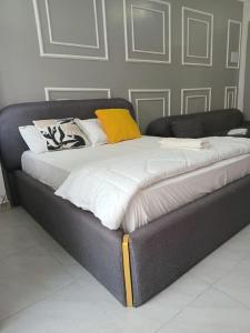 a large bed with white and yellow pillows on it at Lester Deluxe Studio Apartment Near Village Market United Nation and Embassies in Ruaka