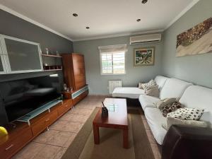 Una sala de estar con un sofá blanco y un televisor. en Villa Loli, Quiet villa with pool, next to beach and city, en Grao de Castellón